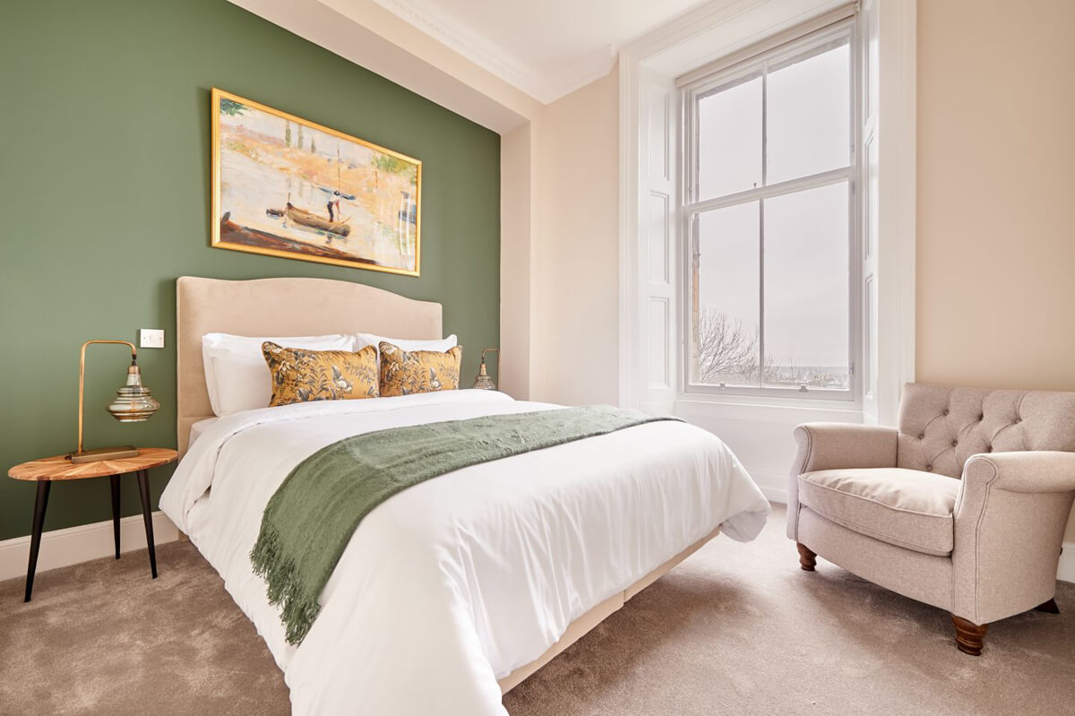 Nowoczesne białe wnętrze z zieloną sofą i roślinami – styl skandynawski 2026.