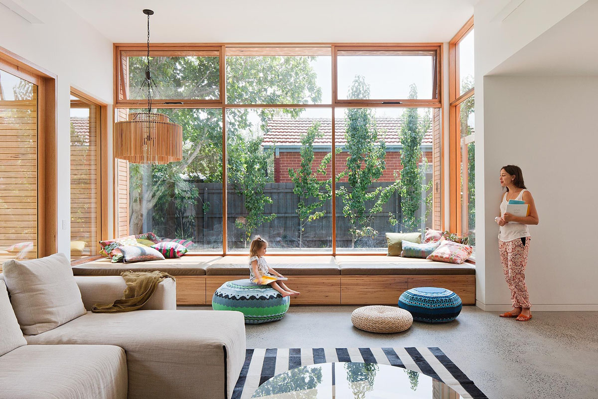 Przytulny kącik na parapecie z poduszkami i widokiem na miasto.