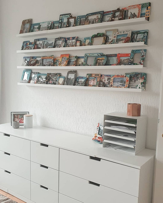 Kilka wąskich półek IKEA tworzy dekorację ścienną z książkami i roślinami. Stylizacja.