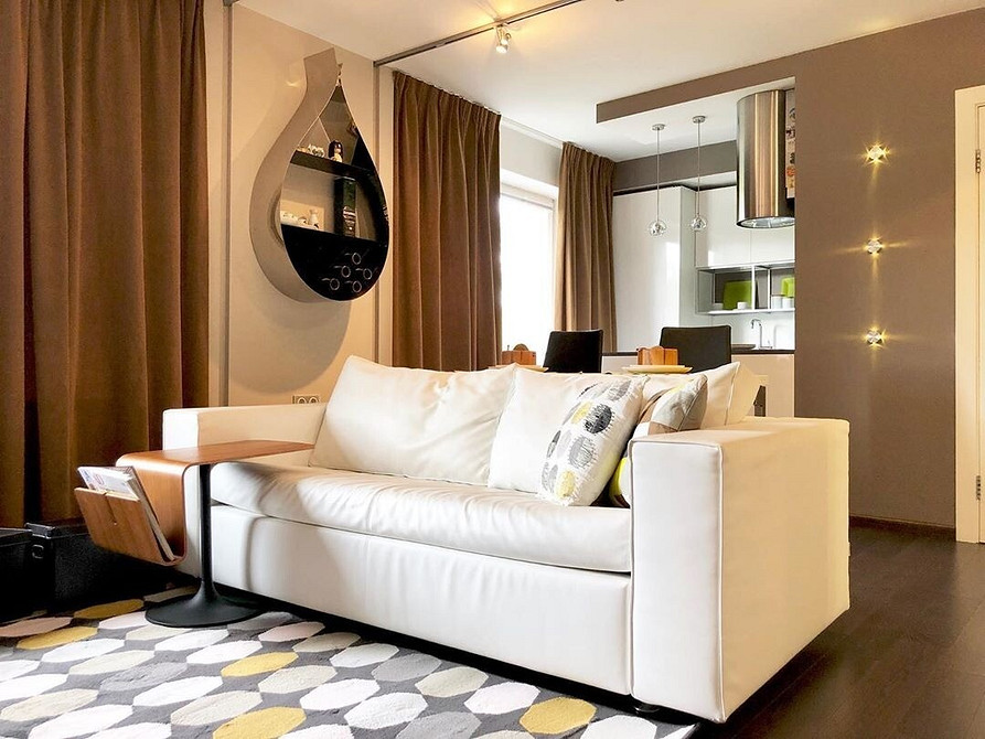 Jasny salon z białymi meblami i dużymi oknami, wypełniony naturalnym światłem.