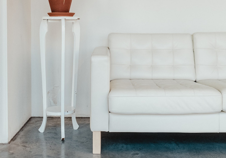 Nowoczesny salon z białym sofaom i elementami dekoracyjnymi z drewna.