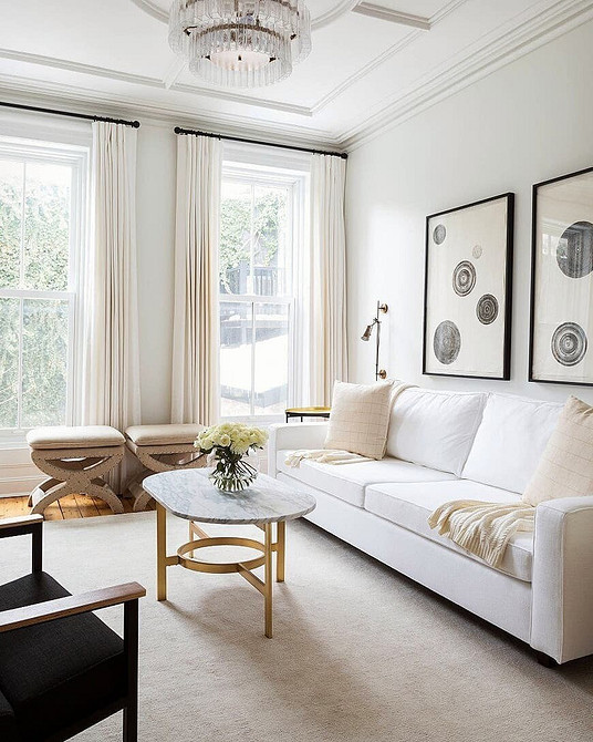 Biały skórzany sofa w nowoczesnym wnętrzu z czarnymi akcentami.