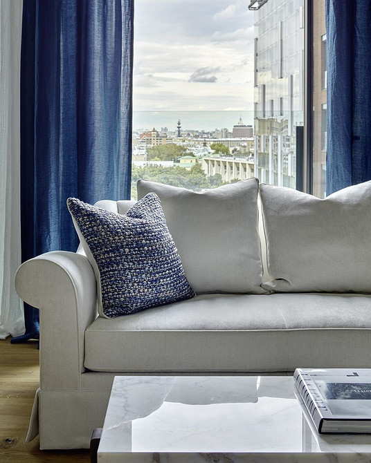 Przestronny salon z dużym białym sofaom i panoramicznymi oknami.