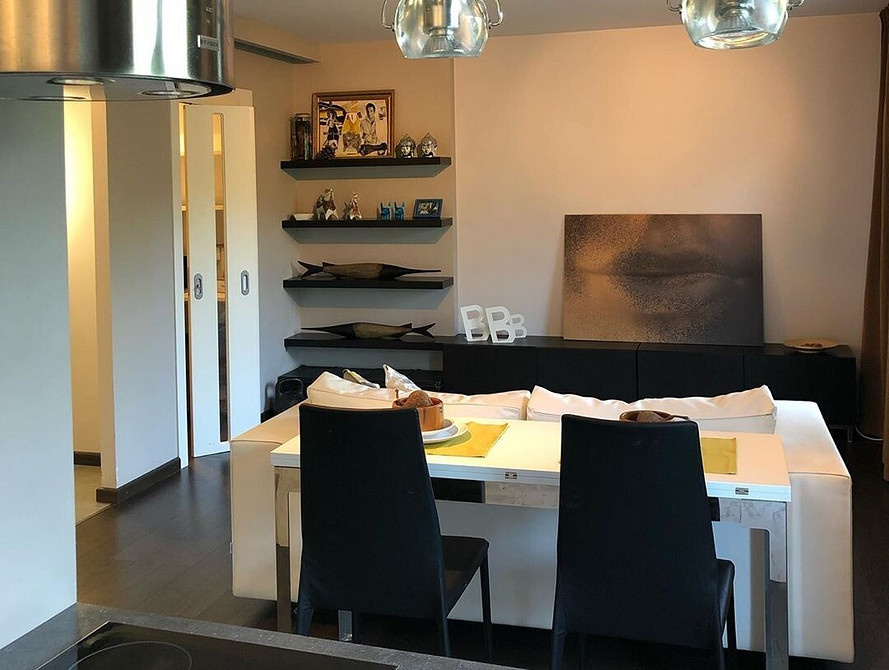 Przytulny zakątek z białym sofaom, pledem i dekoracyjnymi świeczkami.