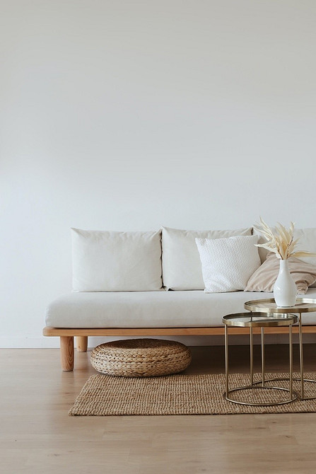 Biała sofa w stylu skandynawskim Biała sofa w salonie w stylu skandynawskim z drewnianymi elementami.