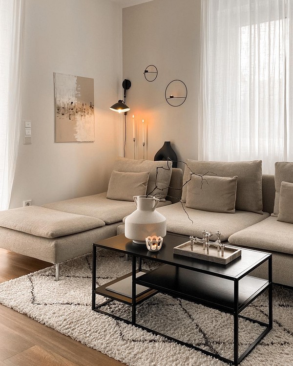 Beżowa sofa w salonie z elementami drewna i zielonymi roślinami.