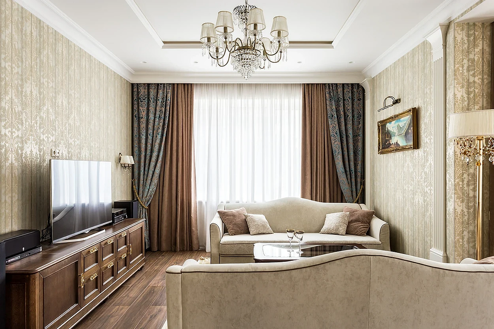 Beżowa kanapa klasyczna Klasyczna aranżacja salonu z elegancką beżową kanapą, drewnianymi meblami i bogactwem tekstyliów.