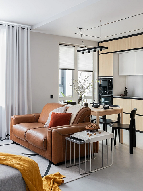 Szara sofa z drewnem Szara sofa z drewnianymi nogami w salonie z roślinami i dekoracjami, wpisująca się w trend loft.