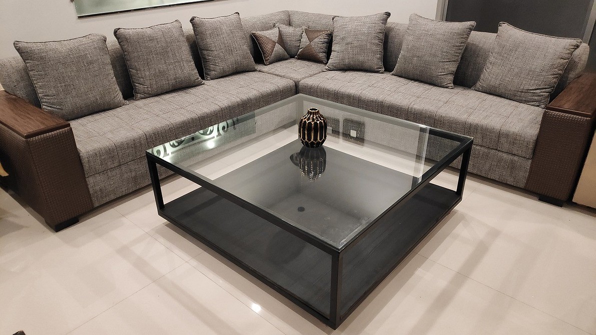 Ciemna sofa z dużą ilością poduszek o różnych teksturach i kolorach.