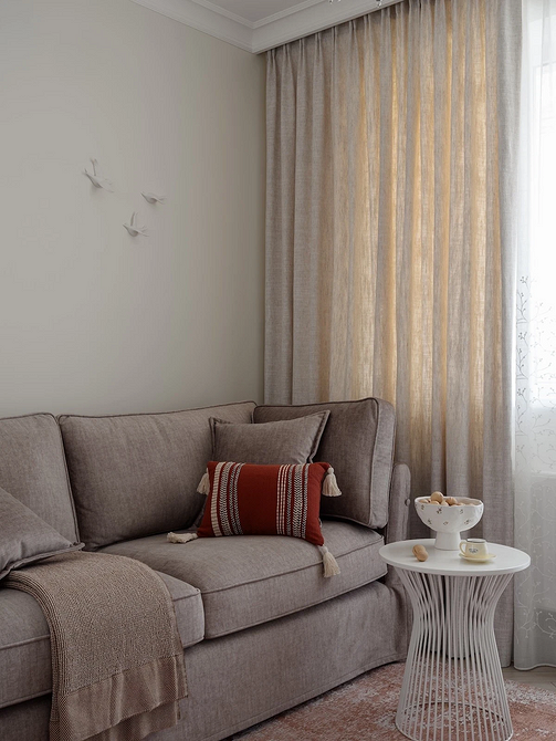 Ciemna sofa w salonie z akcentowanymi ścianami i dekoracjami - trendy 2026.