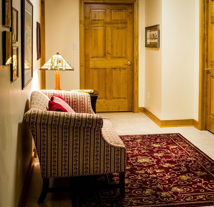 Ciemna sofa z głębokim siedziskiem w salonie z dużą ilością roślin.