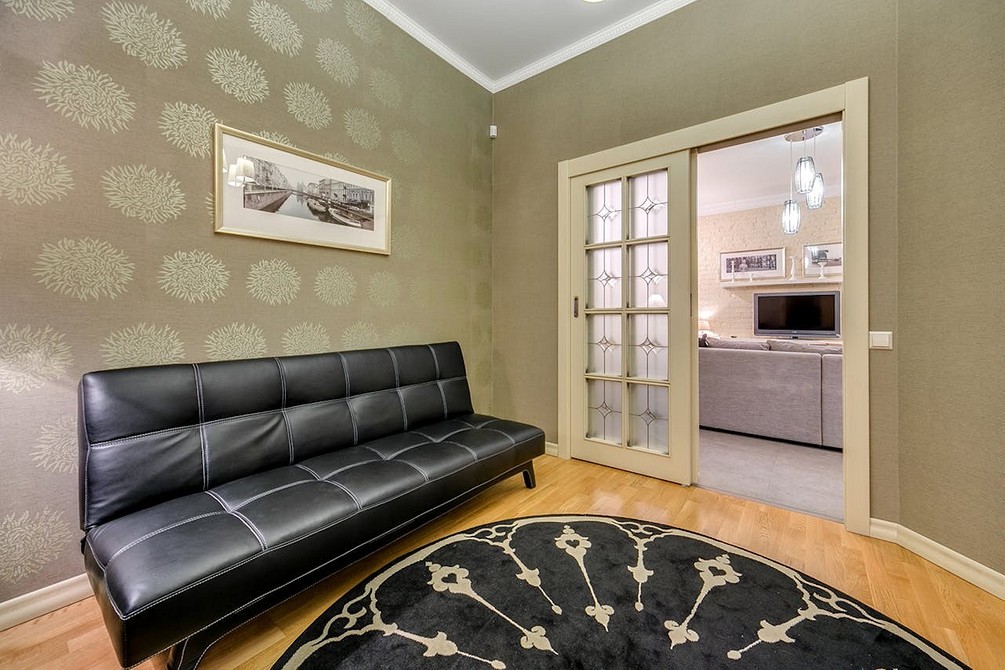 Stylowa, ciemna sofa minimalistyczna z drewnianymi nóżkami w loftowym wnętrzu.