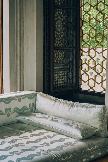 Ciemna sofa z aksamitną tapicerką, w aranżacji z jasnymi akcentami kolorystycznymi.