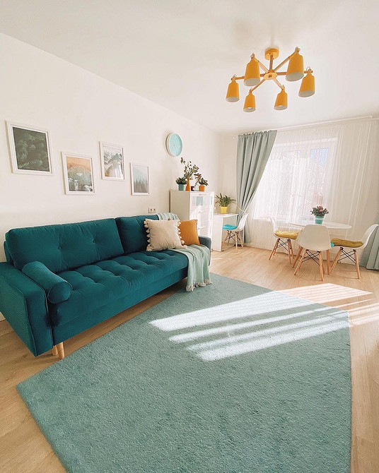Turkusowa kanapa i sztuka Salon z turkusową kanapą, ozdobnymi obrazami na ścianach i drewnianą podłogą.