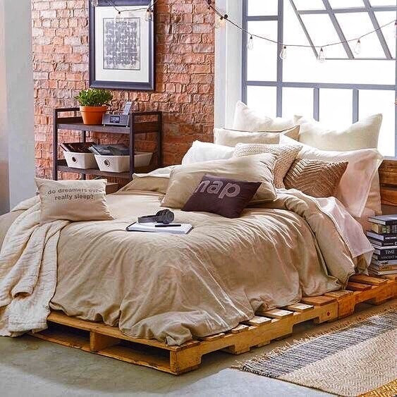 Loftowe łóżko z palet Łóżko z palet z wysokim materacem w sypialni w stylu loft