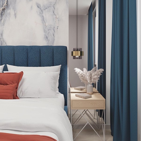 Miękki zagłówek łóżka o oryginalnym kształcie, obity jasną tkaniną.