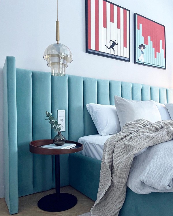 Stylowa sypialnia z łóżkiem z miękkim zagłówkiem w neutralnym kolorze.