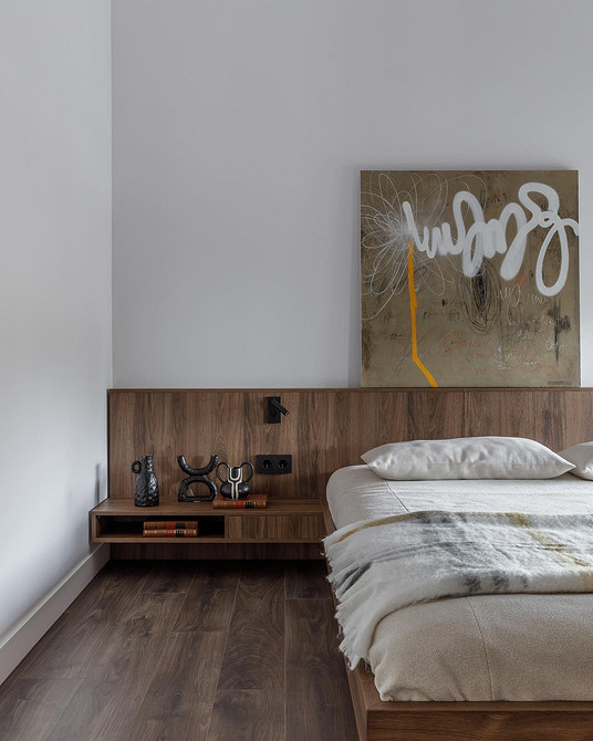 Duże łóżko z tapicerowanym zagłówkiem Trendy design 2026: sypialnia z dużym, miękkim łóżkiem i wysokim, tapicerowanym zagłówkiem przy ścianie.