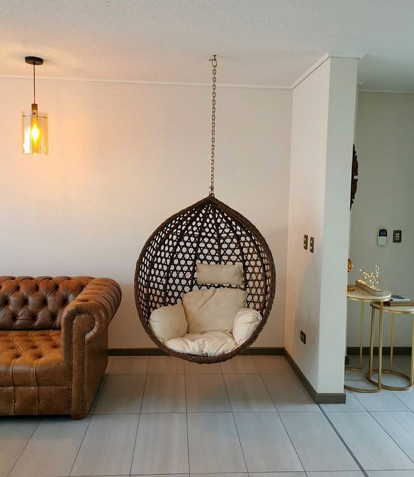 Minimalizm i hamak Fotel wiszący hamak z poduszkami w minimalistycznym wnętrzu małego mieszkania.