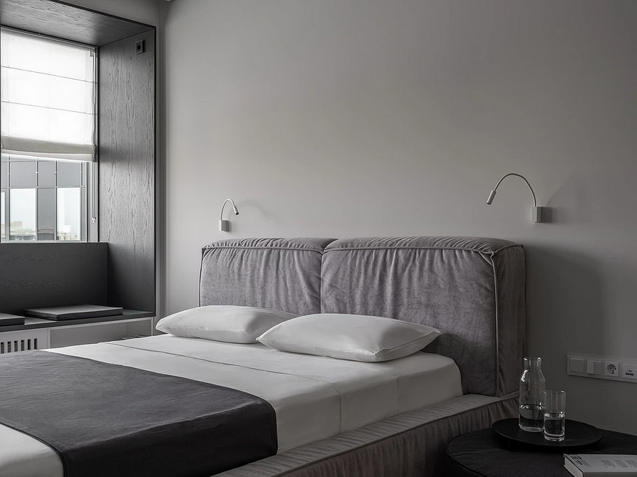 Miękkie szare łóżko Elegancka sypialnia z miękkim szarym łóżkiem i minimalistycznym wystrojem.