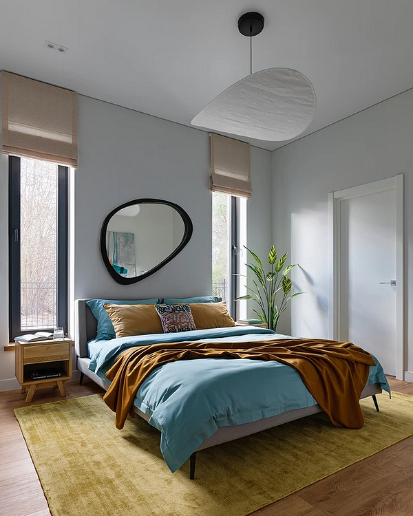 Szare łóżko w sypialni z akcentującą ścianą z geometrycznym wzorem.