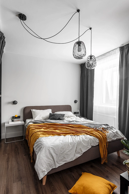 Sypialnia z szarym łóżkiem ozdobiona obrazami i elementami dekoracyjnymi, indywidualny styl.