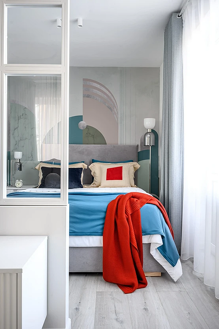 Przytulna sypialnia z szarym łóżkiem, dekoracyjnymi poduszkami i ciepłym oświetleniem.