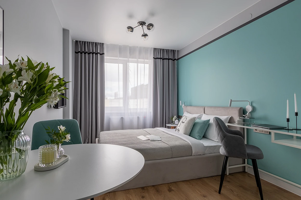 Stylowa sypialnia z szarym łóżkiem, roślinami i elementami artystycznymi.