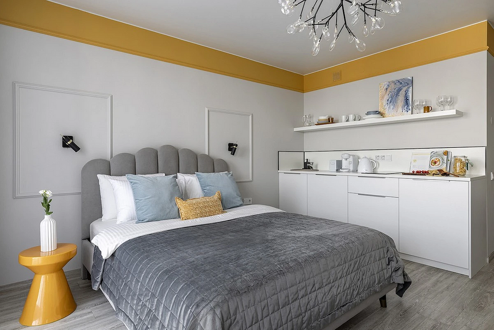 Sypialnia z szarym łóżkiem, drewnianymi szafkami nocnymi i stylową lampą.