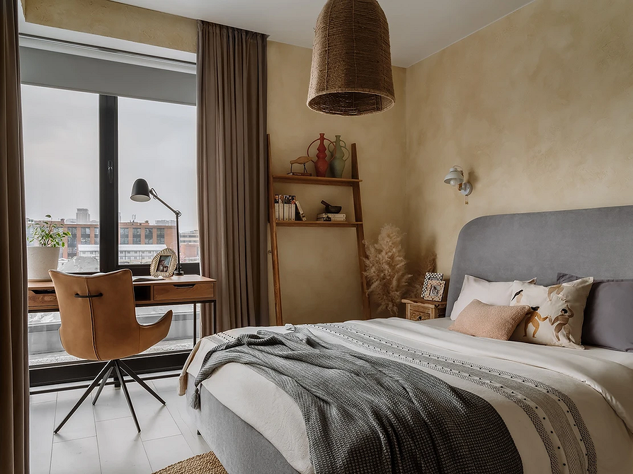 Sypialnia z szarym łóżkiem i jasną pościelą tworząca spokojną atmosferę relaksu.