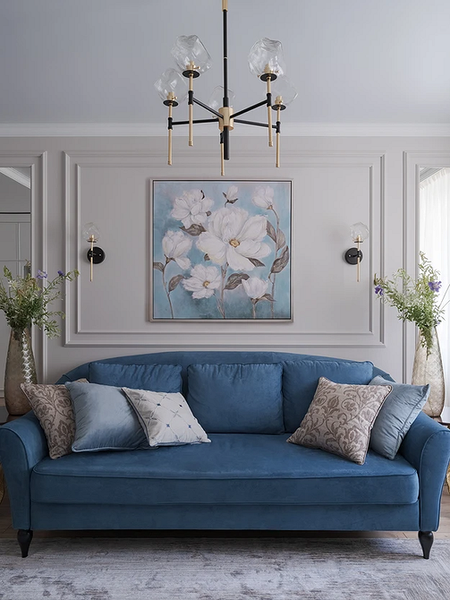 Wnętrze z niebieską sofą, biblioteczką i dekoracyjnym kominkiem w salonie.