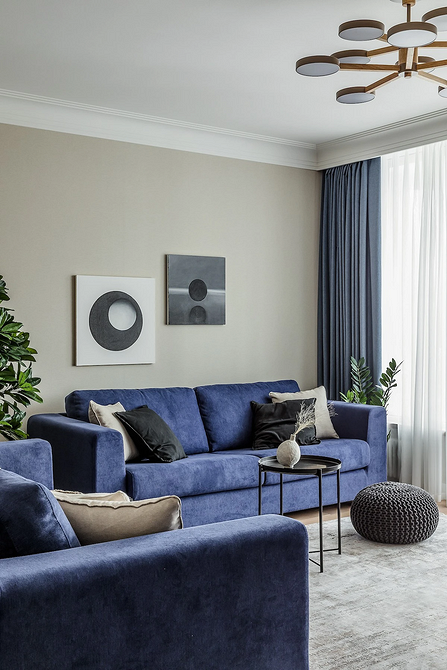 Nowoczesny salon z dużym, niebieskim диваном i kolorowymi poduszkami ozdobnymi.