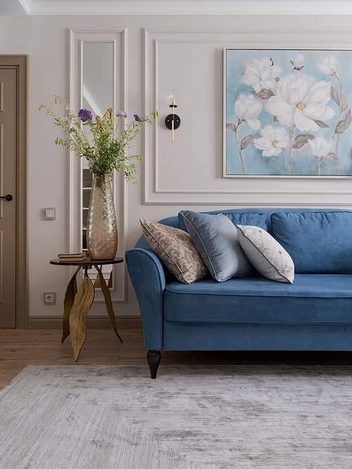 Niebieska sofa w połączeniu z żółtymi elementami dekoracyjnymi w nowoczesnym wnętrzu.