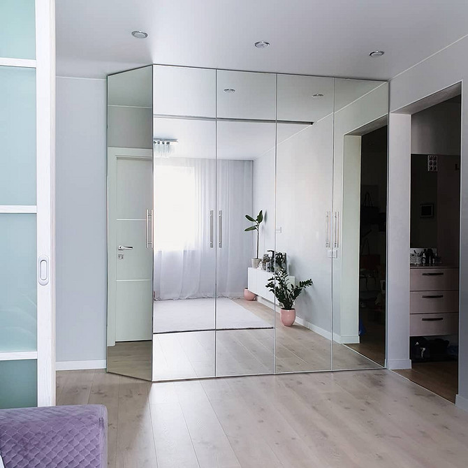 Jasne wnętrze salonu z szafą lustrzaną, która odbija światło.