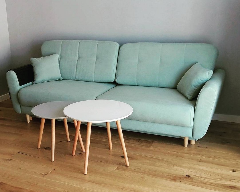 Aranżacja salonu z jasnozieloną sofą i kolorowymi poduszkami dekoracyjnymi.