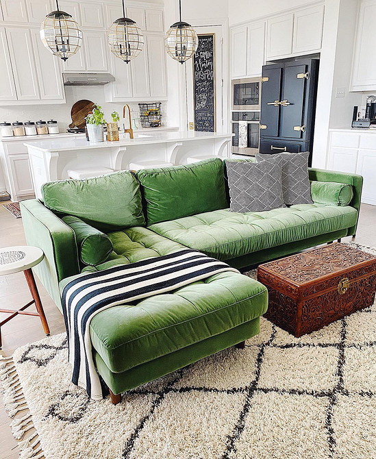 Duża, zielona wygoda Aranżacja z dużą zieloną kanapą, tekstyliami i dekoracyjnymi elementami tworzącymi stylowe wnętrze.