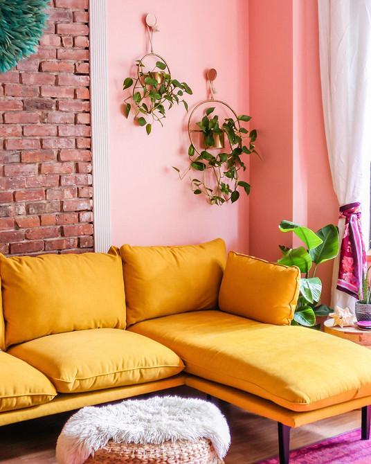 Żółta welurowa sofa w salonie z biblioteczką i lampą - przytulne wnętrze