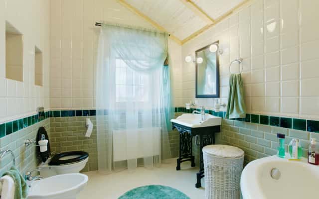 Lampa z abażurem i ceramiczne dekoracje w stylu prowansalskim na szafce nocnej.