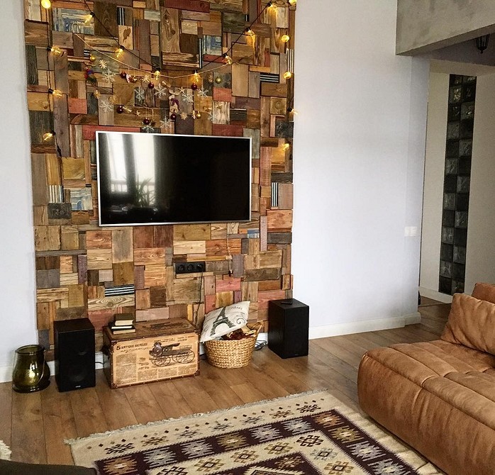 Efektowna ściana z drewna Salon z efektowną drewnianą ścianą, szarą kanapą i elementami dekoracyjnymi