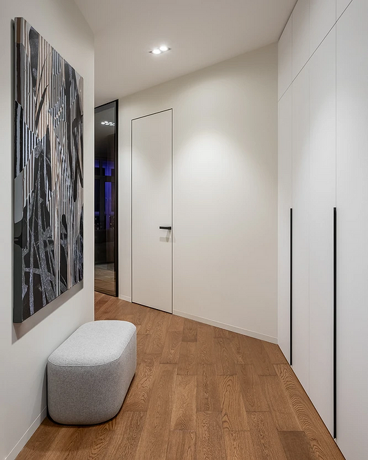 Aranżacja pokoju: białe listwy przypodłogowe pasują do jasnych ścian i drewnianej podłogi.