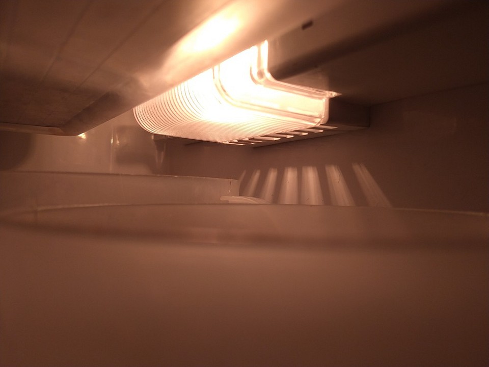 Wymiana żarówki krok po kroku Zdjęcie pokazuje krok po kroku proces wymiany żarówki w lodówce.