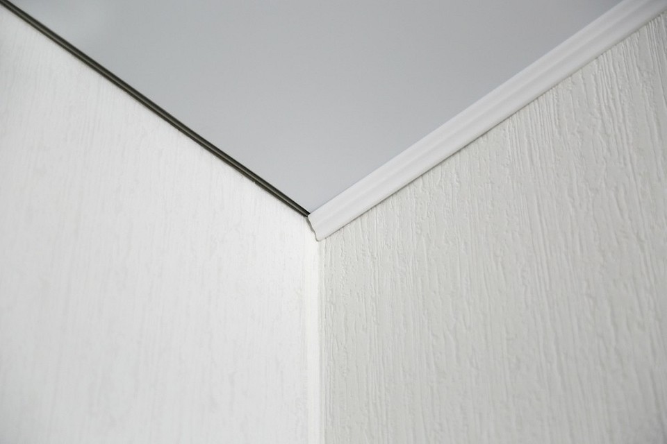 Ilustracja demonstruje technikę łączenia listew sufitowych w narożniku wewnętrznym.