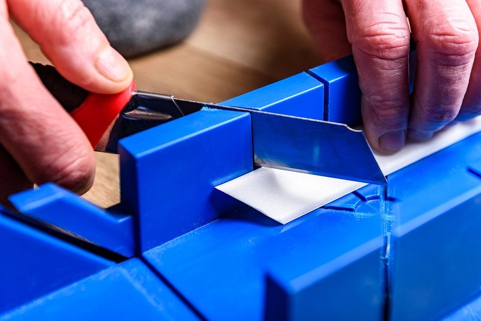 Obraz pokazuje narzędzia potrzebne do cięcia narożników listew sufitowych: piła, skrzynka uciosowa.