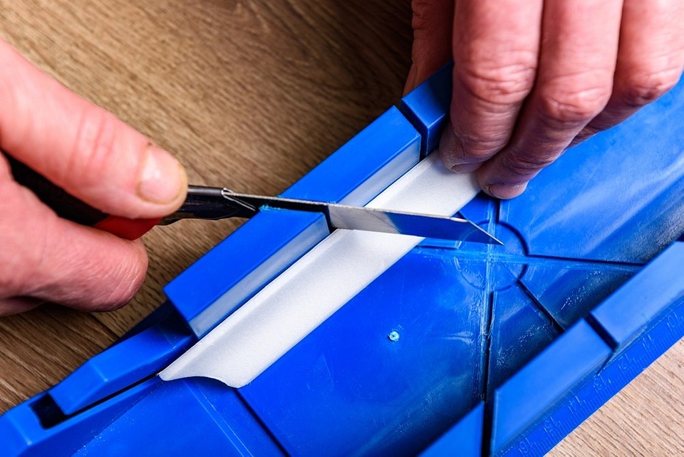 Fotografia instruktażowa cięcia listwy sufitowej pod kątem w skrzynce uciosowej.