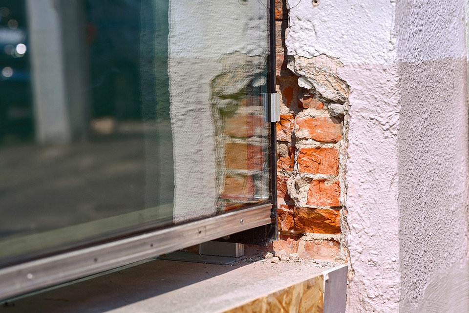 Gruntowanie ościeży Ilustracja pokazująca przygotowanie powierzchni ościeży okiennych przed tynkowaniem, oczyszczenie i gruntowanie.