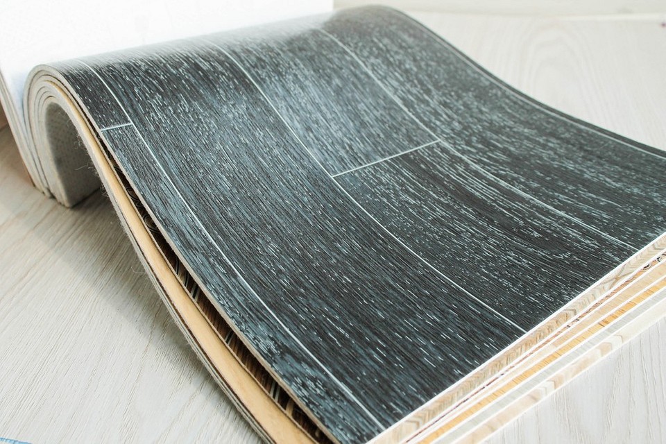 Ilustracja pokazująca proces klejenia linoleum; widoczny aplikator kleju.