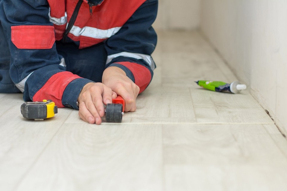 Zdjęcie ukazujące klejenie linoleum komercyjnego; profesjonalny montaż.