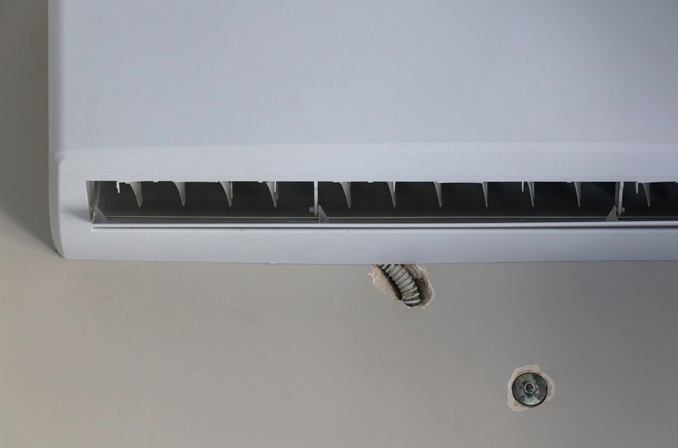 Ilustracja przedstawiająca montaż jednostki zewnętrznej klimatyzacji na ścianie budynku.