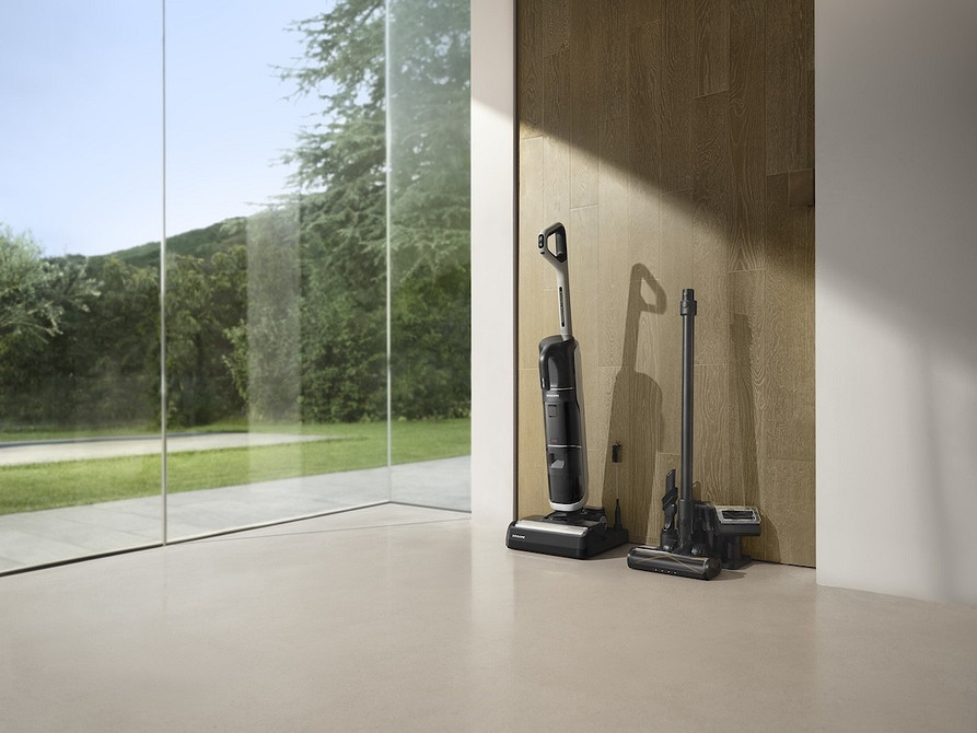 Kobieta relaksuje się, podczas gdy robot sprzątający dba o czystość podłóg.