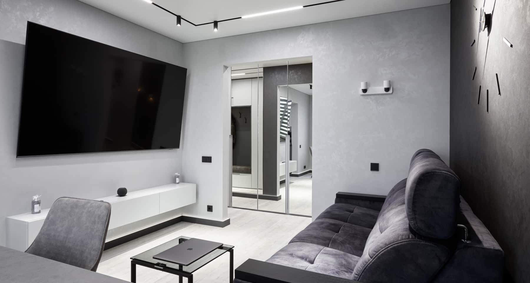 Loftowe wnętrze monochromatyczne Monochromatyczna przestrzeń dzienna z szarą sofą i betonową ścianą, podkreślająca styl loft.